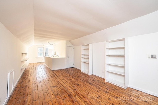 bonus room featuring wood-type flooring, built in features, and vaulted ceiling