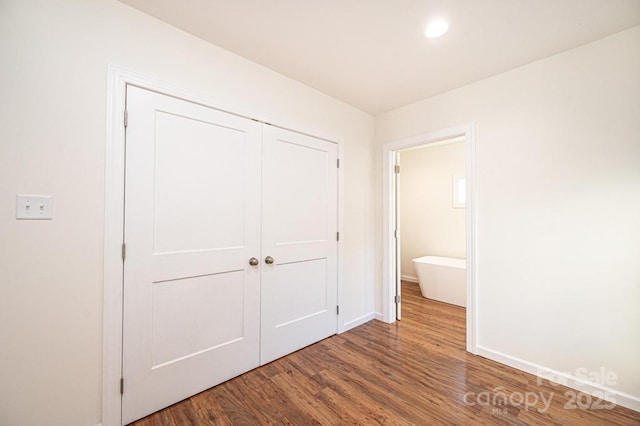 unfurnished bedroom featuring hardwood / wood-style flooring, a closet, and ensuite bathroom