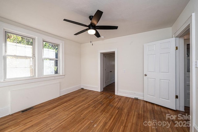 unfurnished bedroom featuring ceiling fan and dark hardwood / wood-style flooring