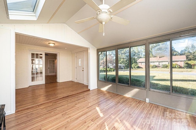 unfurnished sunroom featuring ceiling fan, vaulted ceiling with skylight, and a healthy amount of sunlight