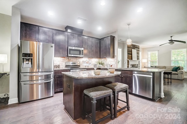 kitchen featuring a center island, appliances with stainless steel finishes, light hardwood / wood-style flooring, and pendant lighting