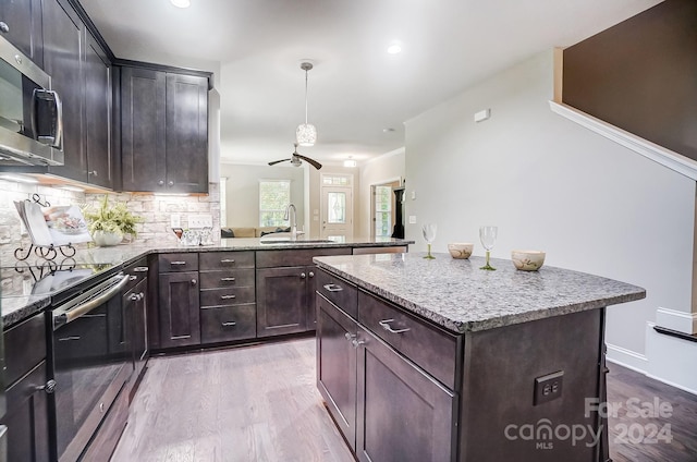 kitchen with hanging light fixtures, light wood-type flooring, stainless steel appliances, sink, and a center island