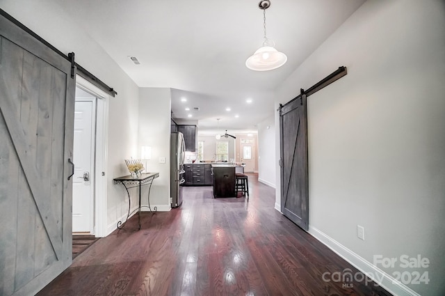 hallway featuring a barn door and dark hardwood / wood-style floors