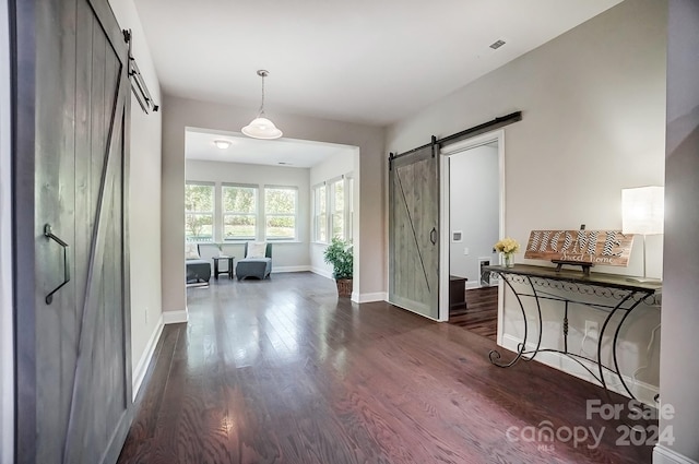 hall with a barn door and dark hardwood / wood-style floors