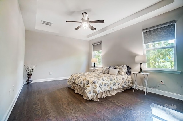 bedroom featuring dark hardwood / wood-style floors, a raised ceiling, and ceiling fan