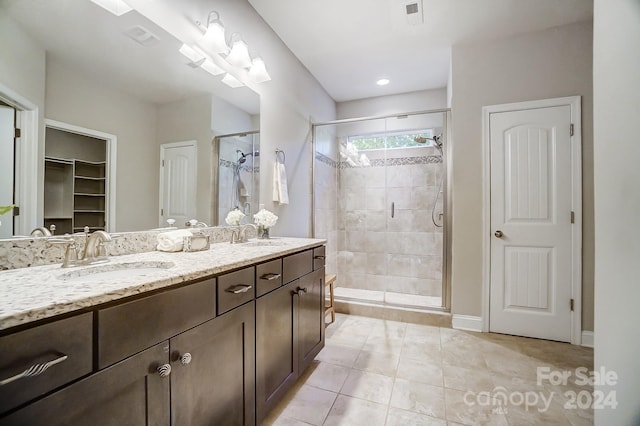 bathroom with a shower with door, tile patterned floors, and vanity