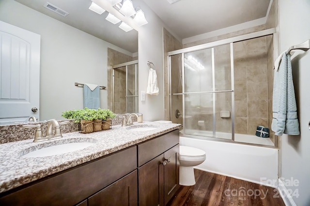 full bathroom with vanity, toilet, hardwood / wood-style flooring, and shower / bath combination with glass door