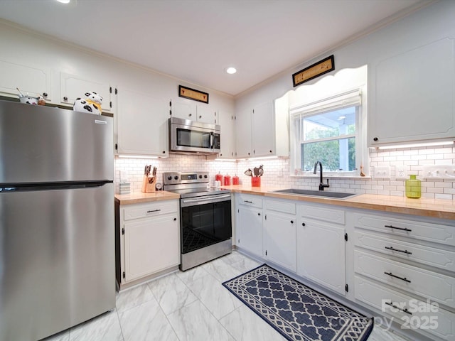 kitchen with stainless steel appliances, a sink, white cabinetry, light countertops, and marble finish floor