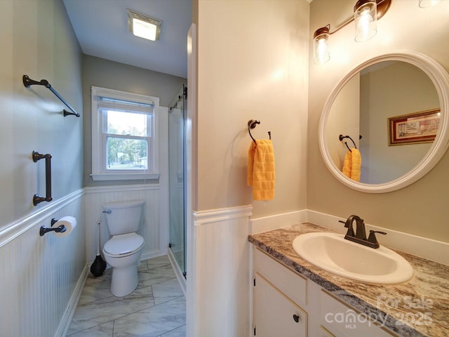 bathroom featuring wainscoting, toilet, marble finish floor, vanity, and a shower stall