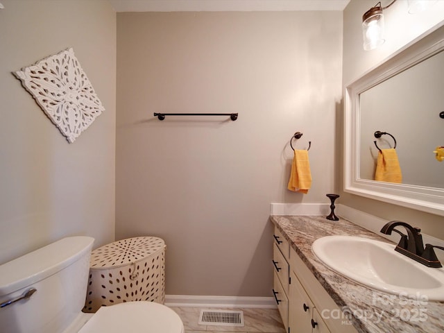 bathroom featuring toilet, baseboards, visible vents, and vanity