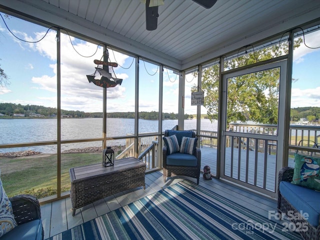 sunroom featuring ceiling fan and a water view