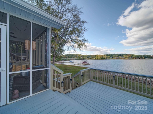 wooden terrace with a sunroom, a water view, and a yard