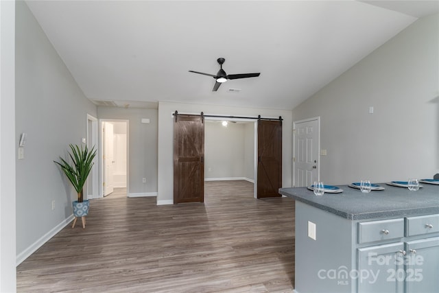 kitchen featuring hardwood / wood-style flooring, ceiling fan, a barn door, and lofted ceiling