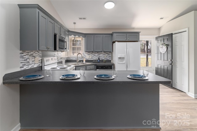 kitchen with white appliances, sink, gray cabinetry, and kitchen peninsula