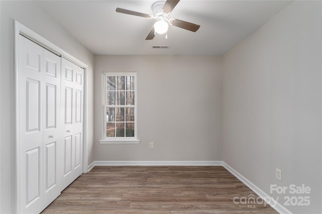 unfurnished bedroom with hardwood / wood-style floors, a closet, and ceiling fan