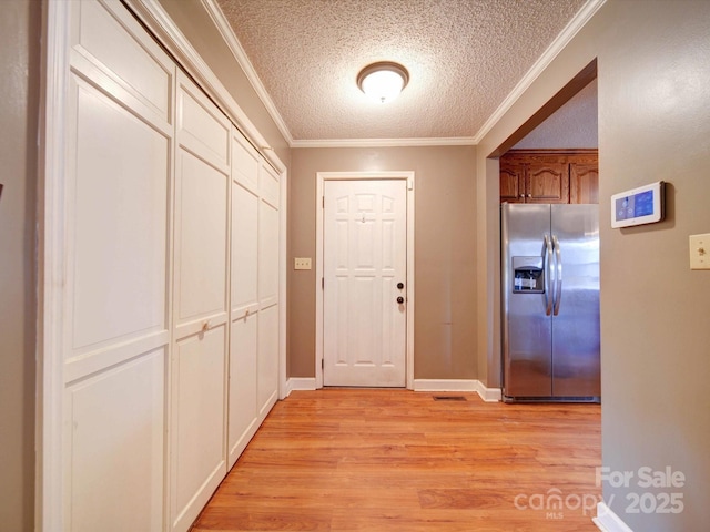 hallway featuring a textured ceiling, light wood finished floors, and crown molding