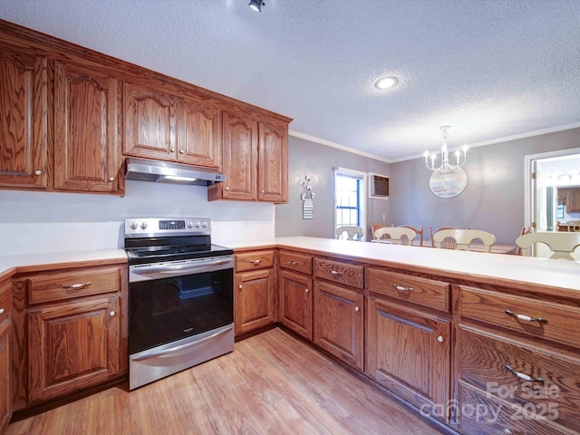 kitchen featuring electric stove, light countertops, brown cabinetry, a peninsula, and under cabinet range hood