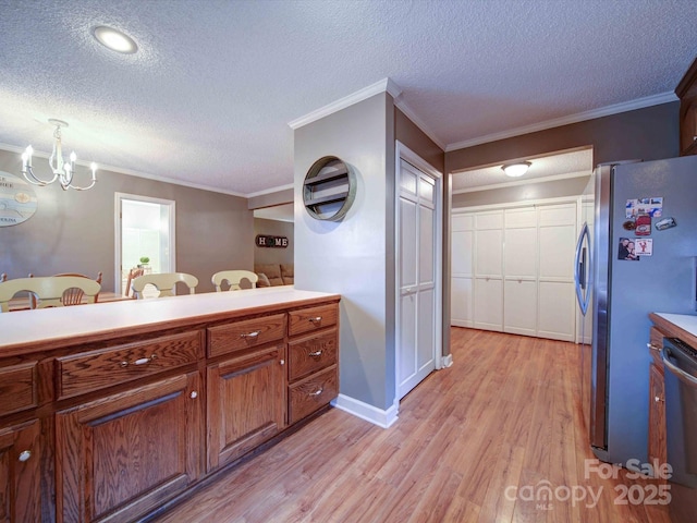 kitchen with decorative light fixtures, stainless steel appliances, light countertops, a textured ceiling, and light wood-style floors