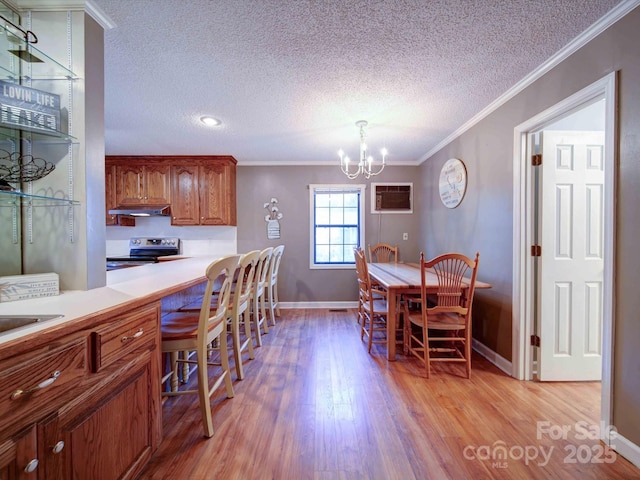 dining room featuring an inviting chandelier, a wall unit AC, light wood-style flooring, and crown molding