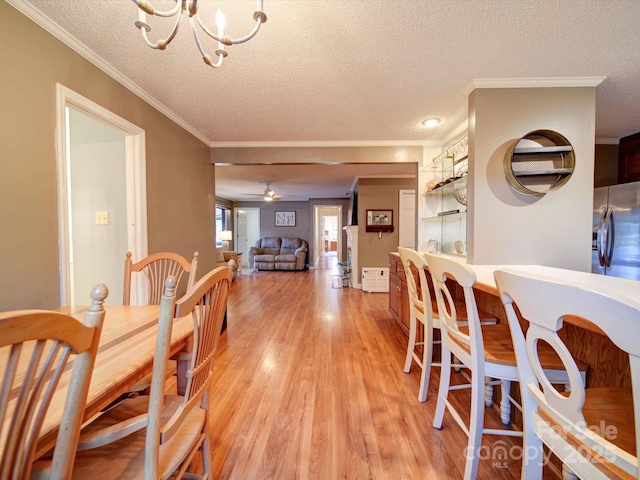 dining room featuring a textured ceiling, ornamental molding, ceiling fan with notable chandelier, and light wood-type flooring