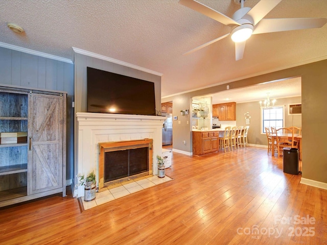 unfurnished living room featuring light wood finished floors, ornamental molding, a textured ceiling, and ceiling fan with notable chandelier