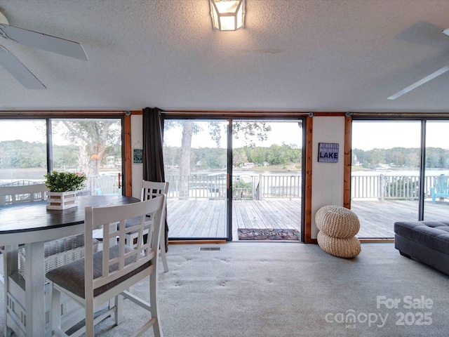 sunroom with a water view, ceiling fan, and visible vents