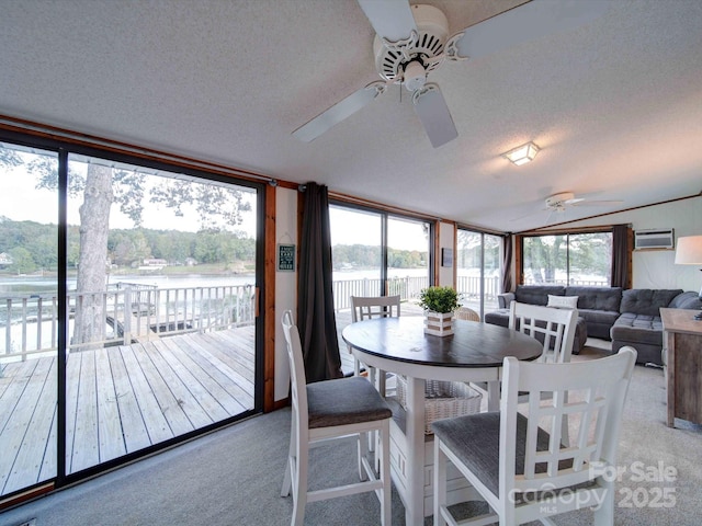 sunroom featuring a water view, ceiling fan, vaulted ceiling, and a wealth of natural light