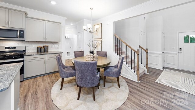 dining room with crown molding, wood-type flooring, and a chandelier