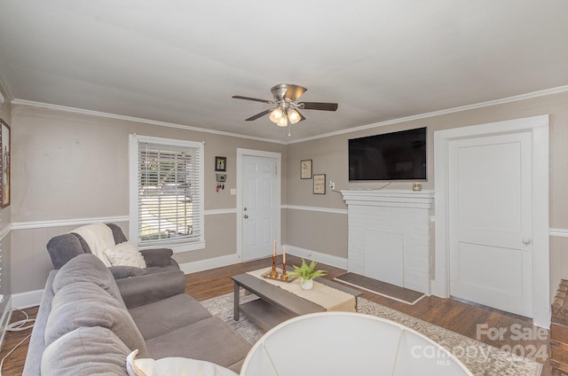 living room with crown molding, a brick fireplace, hardwood / wood-style flooring, and ceiling fan