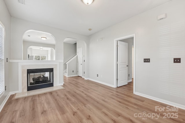 unfurnished living room with a multi sided fireplace and light hardwood / wood-style flooring