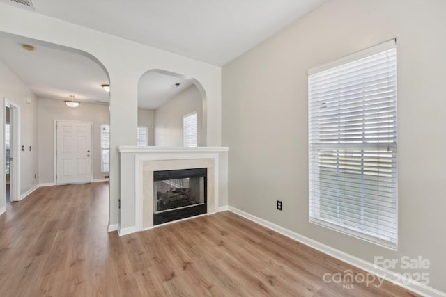 unfurnished living room with a multi sided fireplace and light hardwood / wood-style flooring