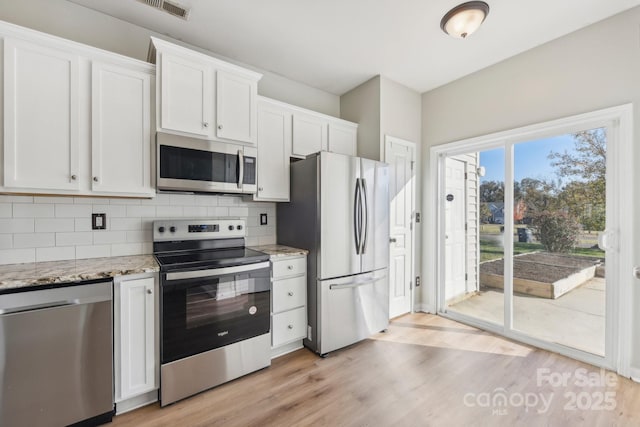 kitchen with backsplash, white cabinetry, and stainless steel appliances