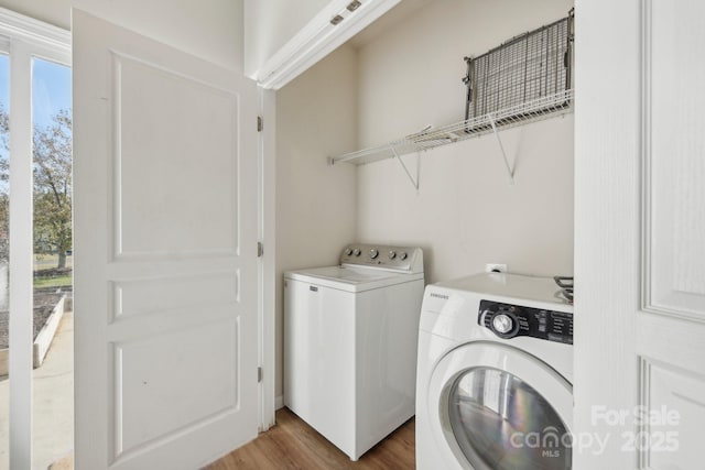 clothes washing area featuring wood-type flooring and separate washer and dryer