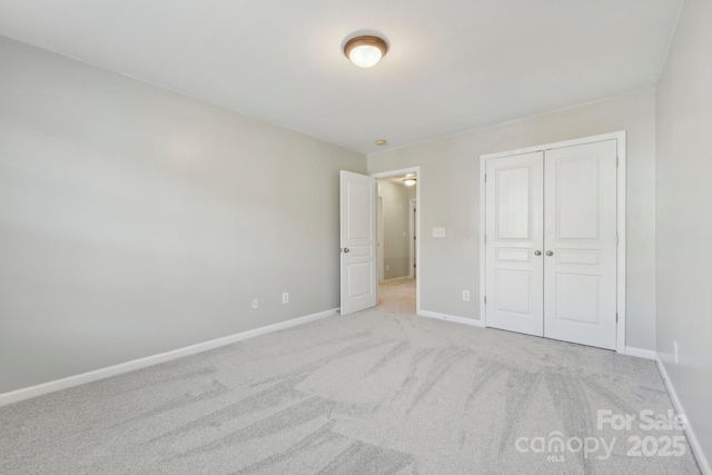 unfurnished bedroom with light colored carpet and a closet