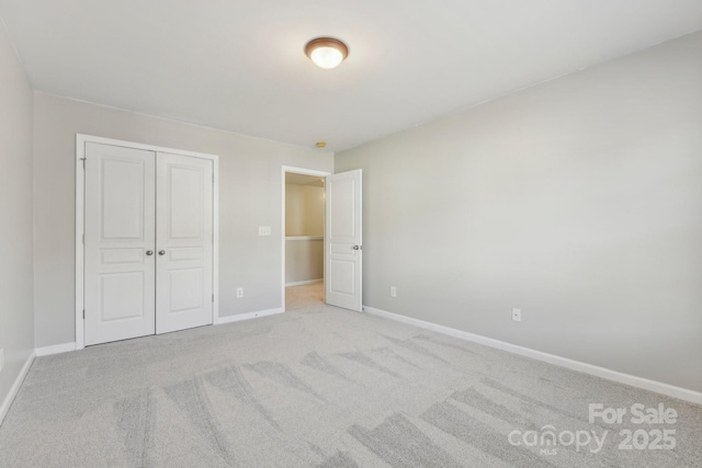 unfurnished bedroom featuring light colored carpet and a closet