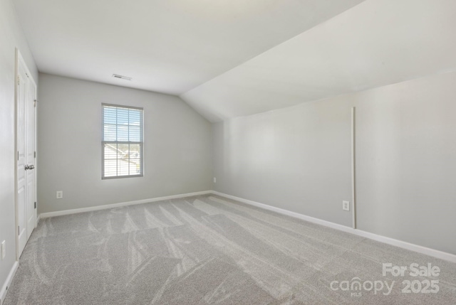 additional living space featuring light carpet and vaulted ceiling