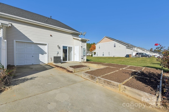 back of property featuring central AC unit, a garage, and a lawn