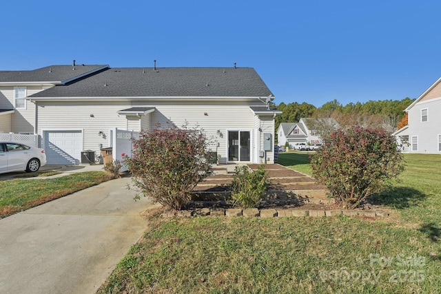 rear view of house with a garage and a yard