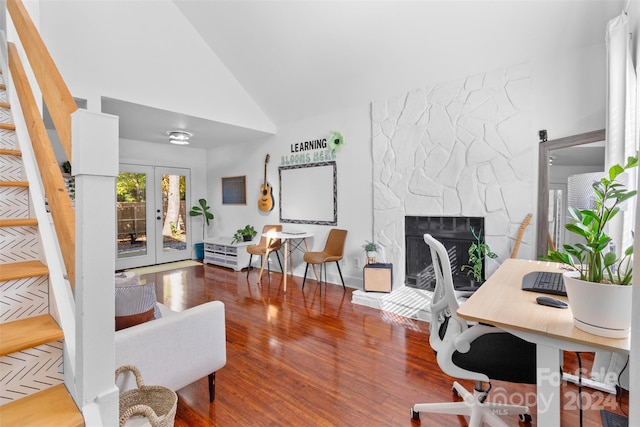 home office with french doors, a stone fireplace, wood-type flooring, and high vaulted ceiling