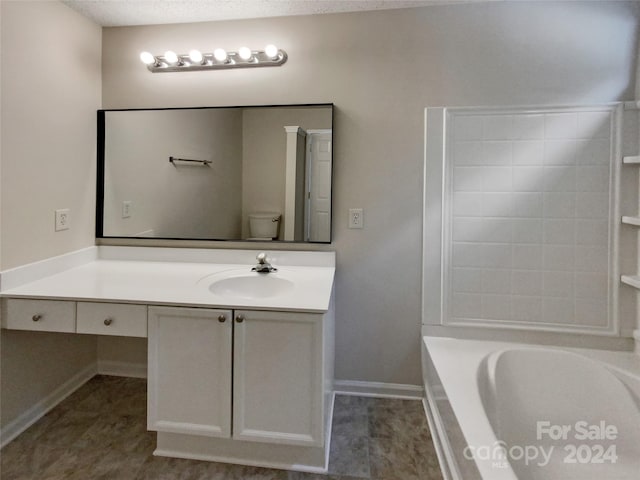 bathroom with vanity, a tub, a textured ceiling, and toilet