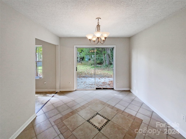 unfurnished dining area featuring a textured ceiling, a chandelier, and light tile patterned floors