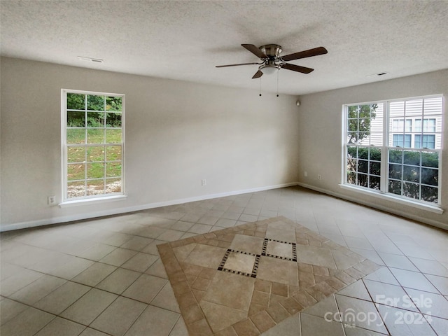 empty room with a textured ceiling, light tile patterned floors, and plenty of natural light