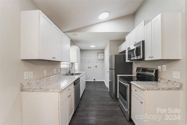 kitchen with appliances with stainless steel finishes, white cabinetry, sink, and vaulted ceiling