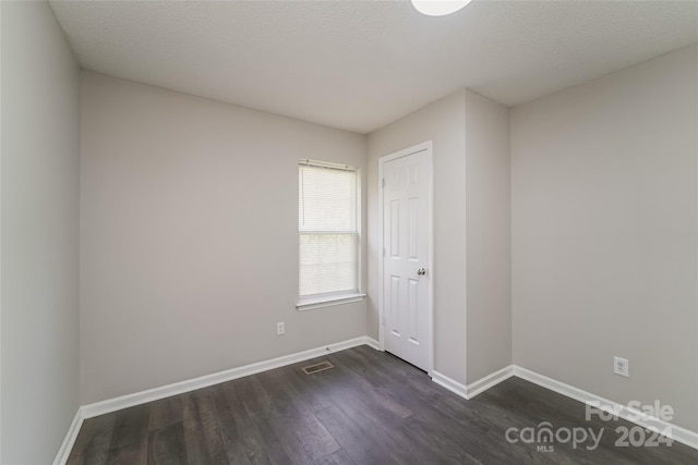 empty room featuring a textured ceiling and dark hardwood / wood-style floors