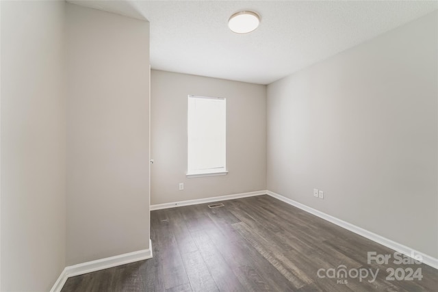 unfurnished room with a textured ceiling and dark hardwood / wood-style flooring