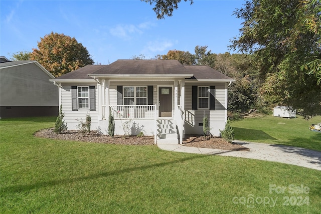 ranch-style home featuring covered porch and a front yard