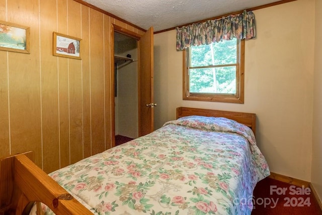 bedroom featuring a closet, wooden walls, and crown molding