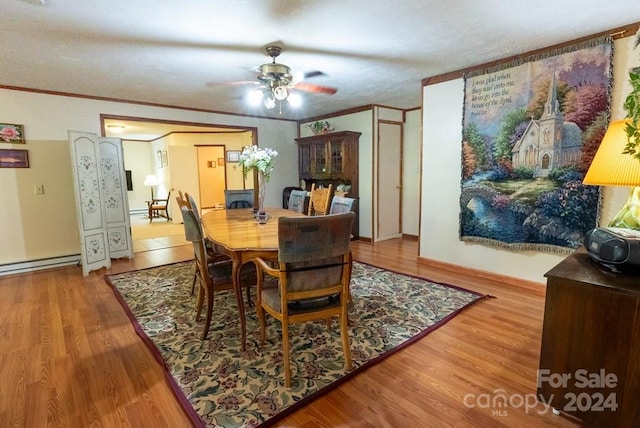 dining space with crown molding, hardwood / wood-style flooring, a baseboard radiator, and ceiling fan