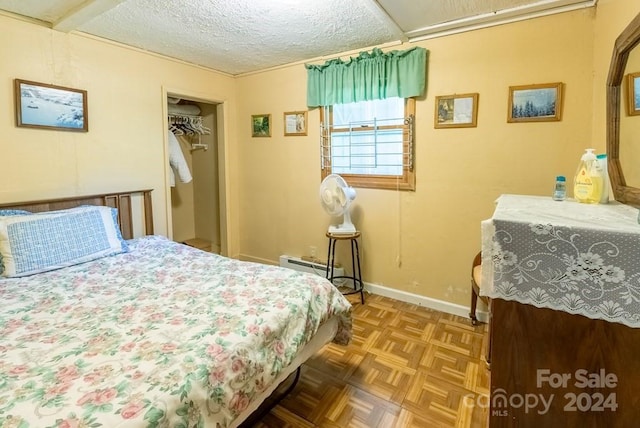 bedroom featuring a closet, parquet floors, a textured ceiling, and a baseboard heating unit