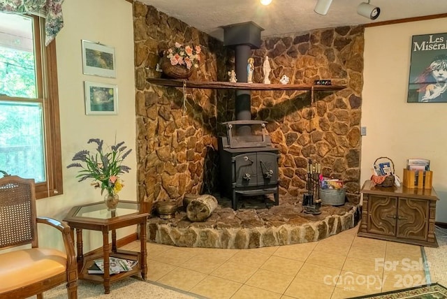 living room featuring a wood stove, tile patterned floors, and a wealth of natural light